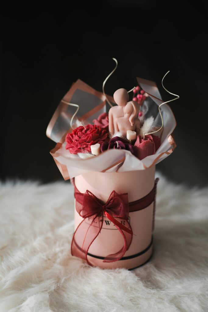Elegant floral arrangement in a gift box featuring roses and a unique artistic figurine, perfect for romantic occasions.